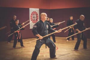 a group of people in black karate uniforms holding sticks